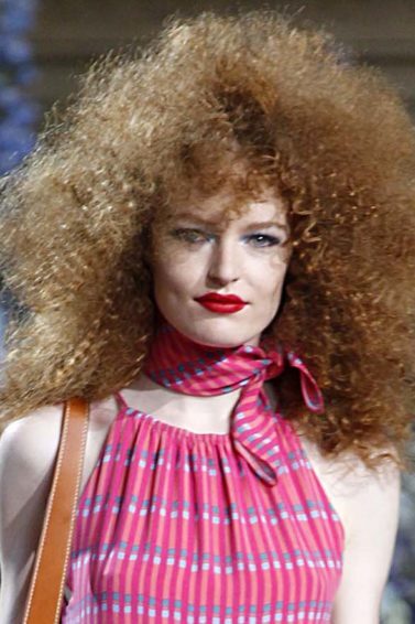 Mulher usa cabelo volumoso indefinido na passarela