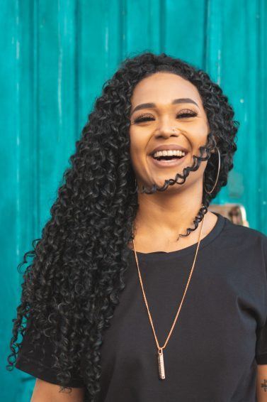 mulher com cabelo cacheado castanho escuro sorrindo