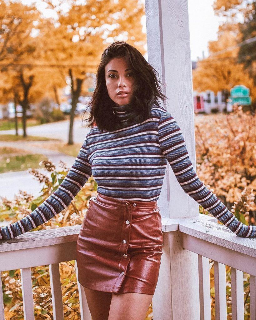Mulher com cabelo castanho médio com blusa listrada e saia caramelo