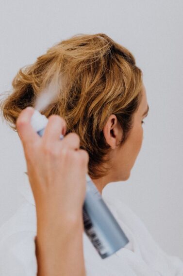 mulher borrifando shampoo a seco no cabelo