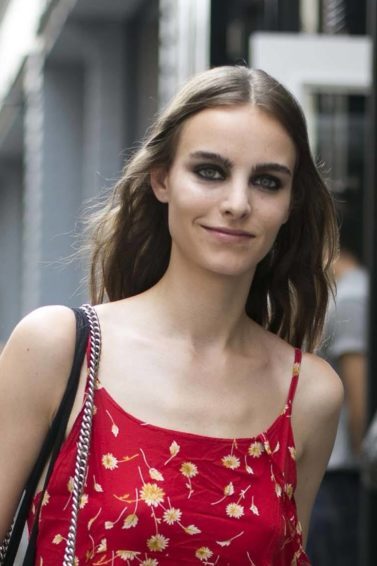 Mulher usa cabelo partido ao meio e usa vestido vermelho com flores claras