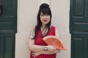 Mulher oriental usa vestido vermelho, leque e topete com franja, um dos tipos de topete