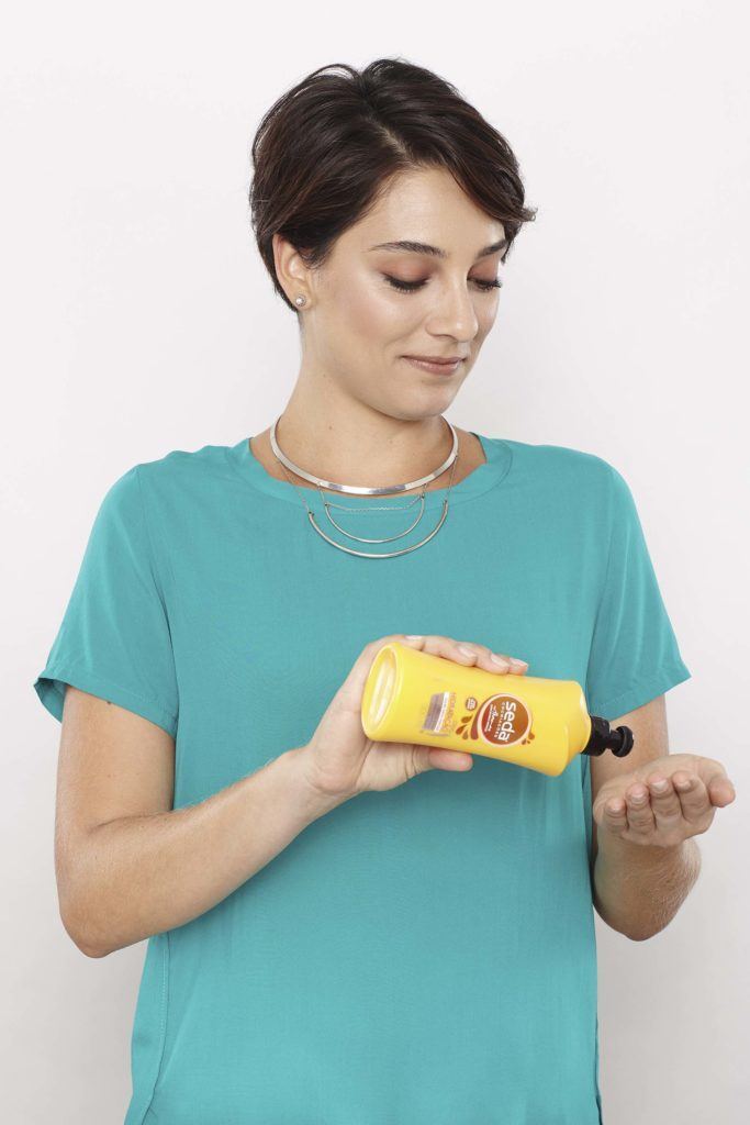 Mulher passando creme de tratamento nos cabelos
