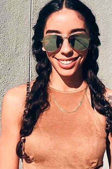 Mulher usa top marrom com barriga de fora e trança enrolada no cabelo