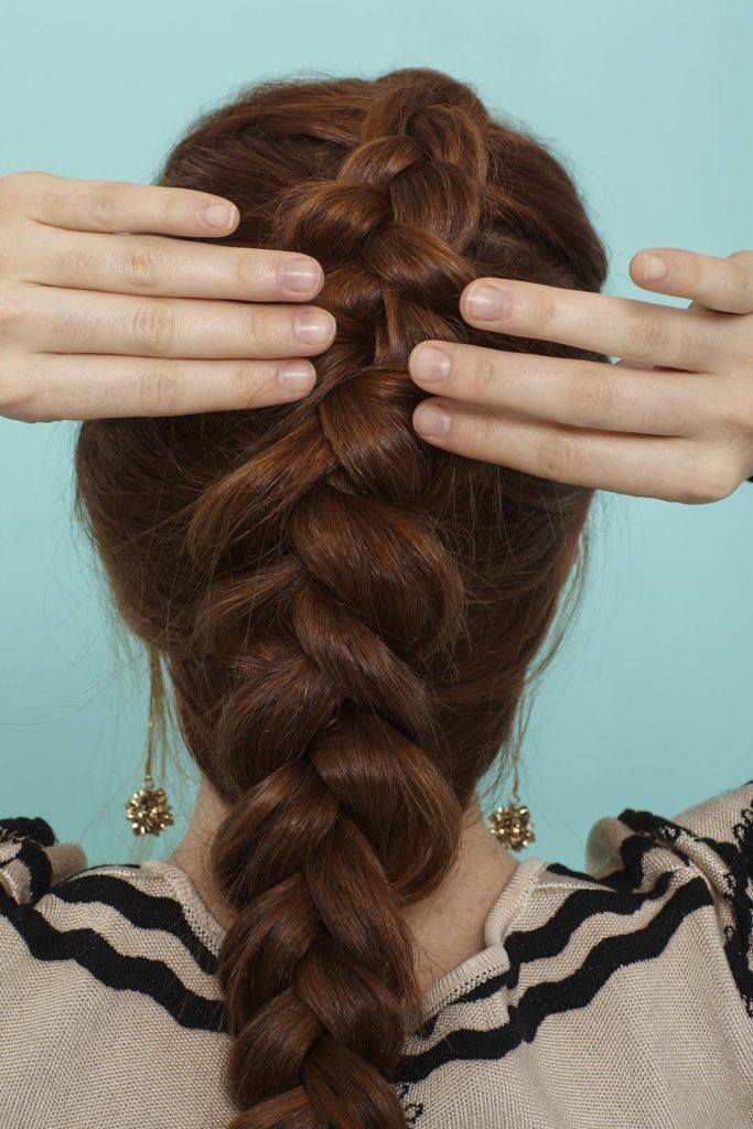 modelo com uma trança holandesa embutida no cabelo ruivo