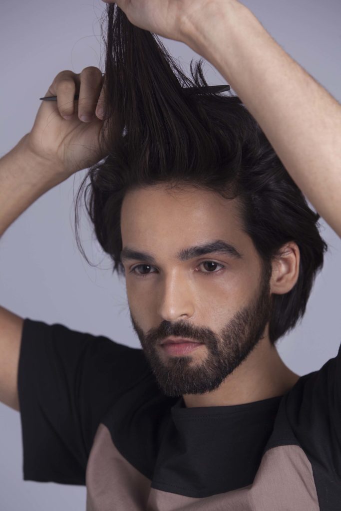 Com um pente, modelo desfia o cabelo que vai receber trança masculina