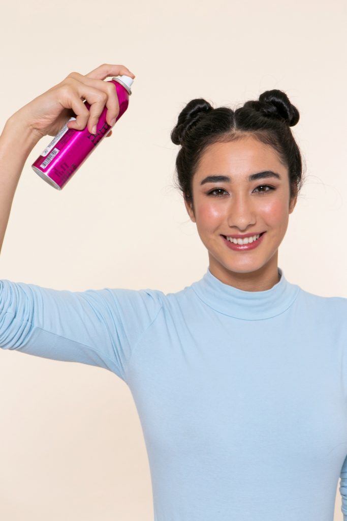modelo com tranças no cabelo invertidas com coque duplo aplicando shampoo a seco