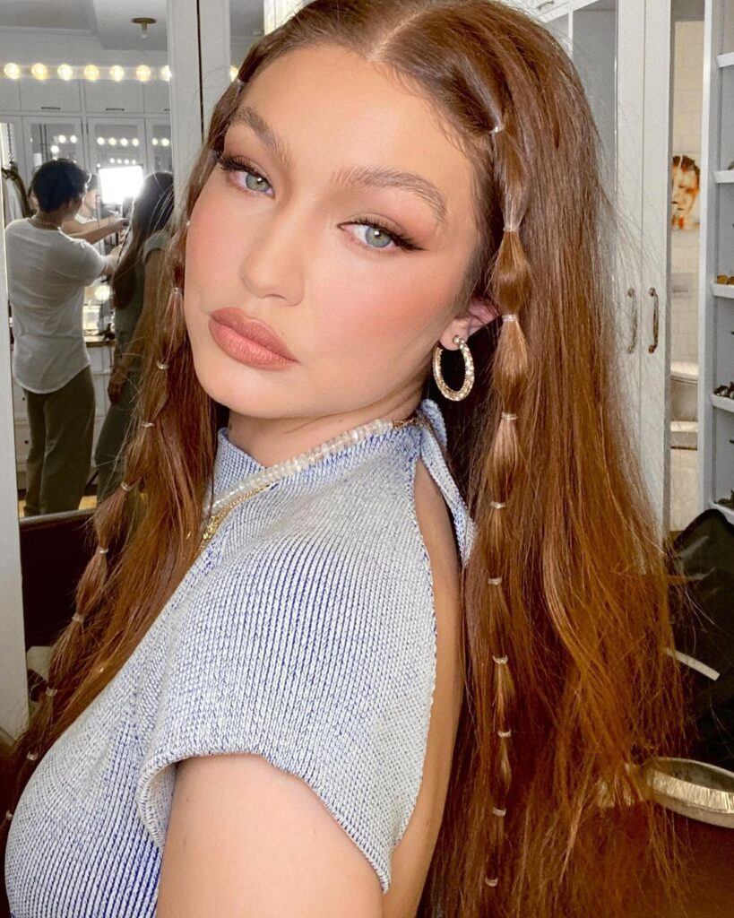 Modelo Gigi Hadid usando roupa clara e um dos penteados com tranças: a trança bolha só na frente do cabelo ruivo