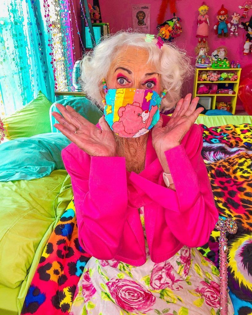 mulher idosa com acessórios de cabelo coloridos e máscara de