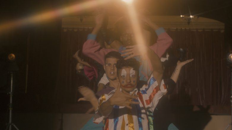 pessoas lgbtqia+ enfileiradas movimentando os braços