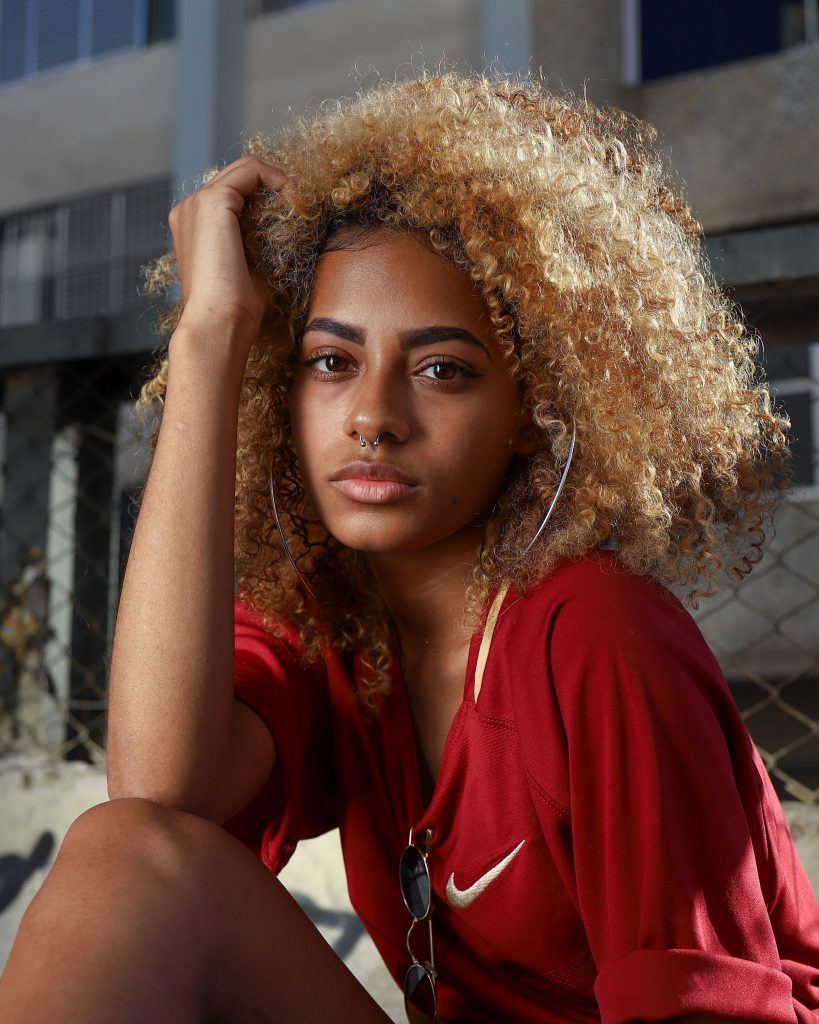 mulher com cabelo loiro longo crespo