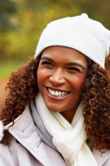 como cuidar do cabelo no frio: modelo com cabelo crespo e touca
