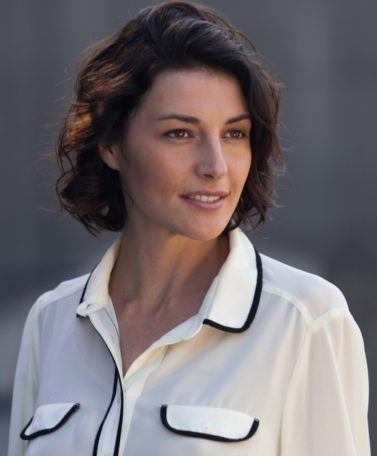 Mulher usa camisa branca com detalhes escuros e, no cabelo, messy bob perfeito