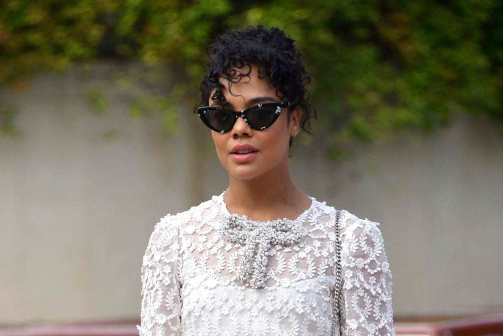 A atriz Tessa Thompson com cabelo cacheado curto e coque alto