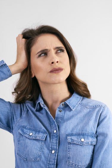 mulher com a mão no cabelo e cara de preocupada