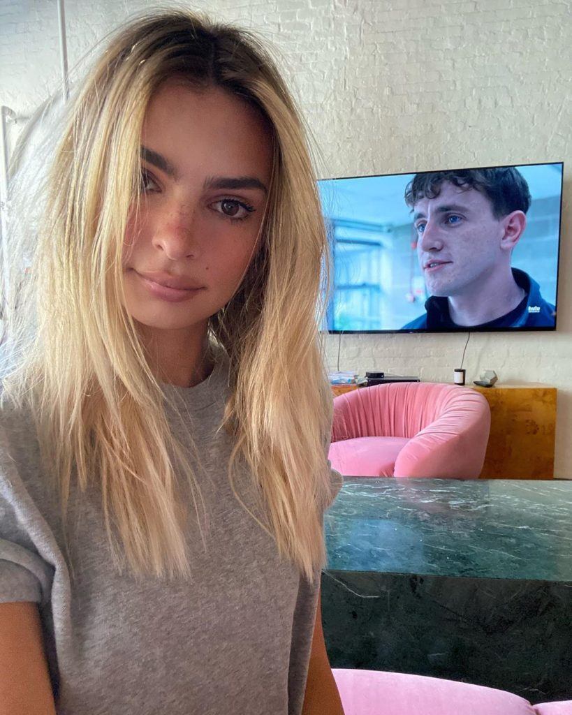 a atriz emily ratajkowski com o cabelo loiro longo e camiseta cinza