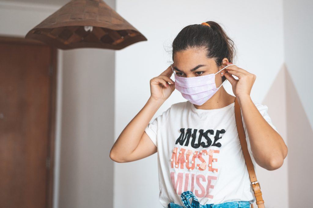 mulher com o cabelo preso colocando a máscara
