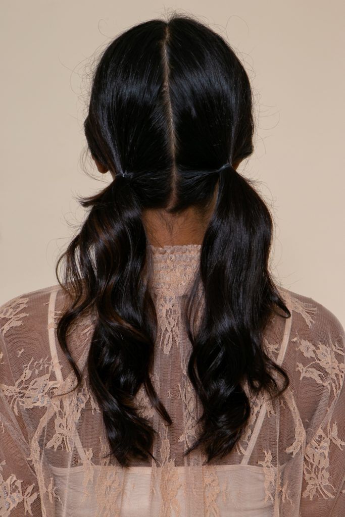modelo morena de cabelo preto longo e levemente ondulado com dois rabos de cavalo baixos