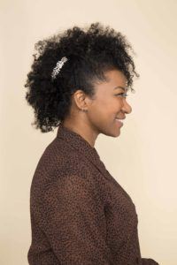 Mulher com cabelo afro preso por acessório prateado