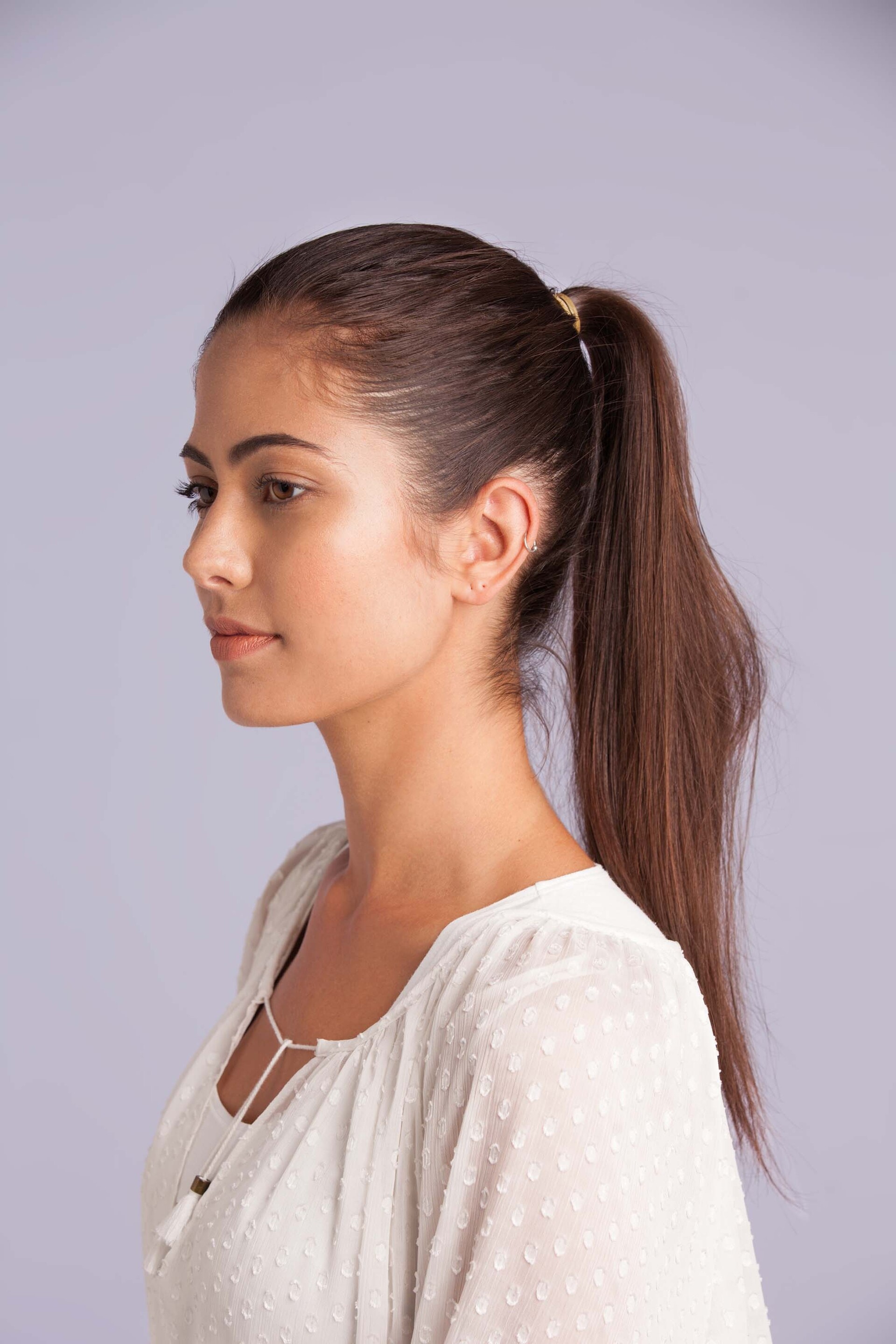 Modelo com cabelos longos e lisos usa rabo de cavalo alto, penteado fácil de fazer sozinha