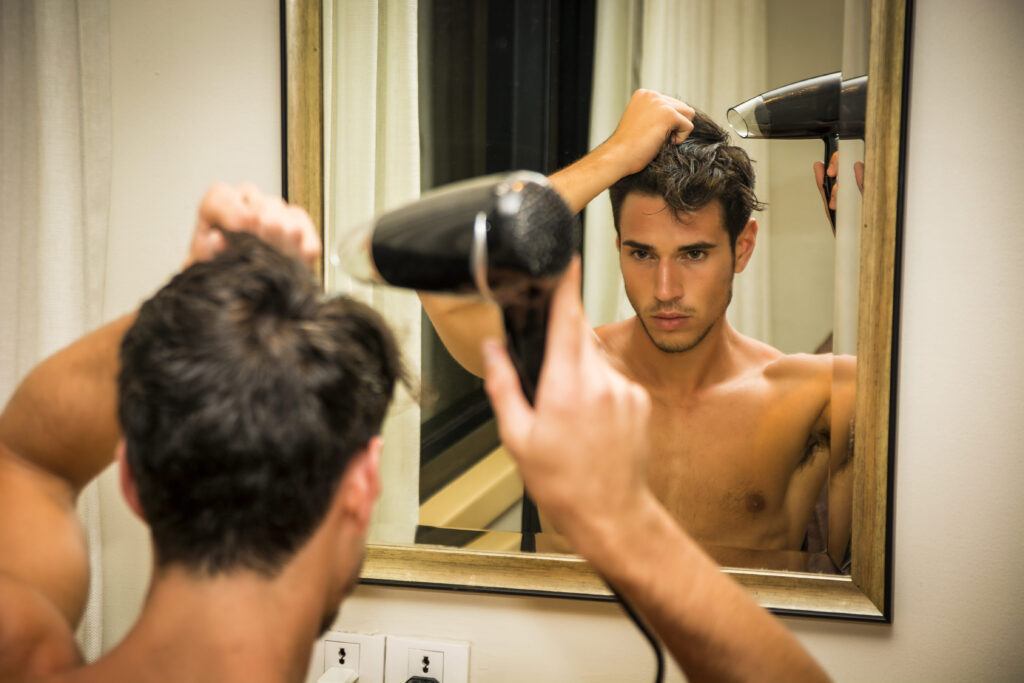 homem secando o cabelo para disfarçar entradas