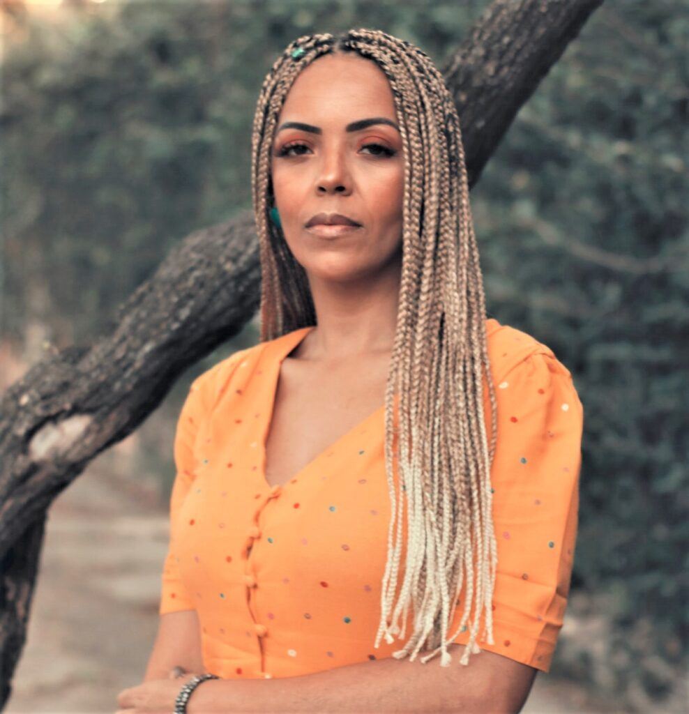 Mulher ao ar livre com roupa laranja e trança estilo box braids mel