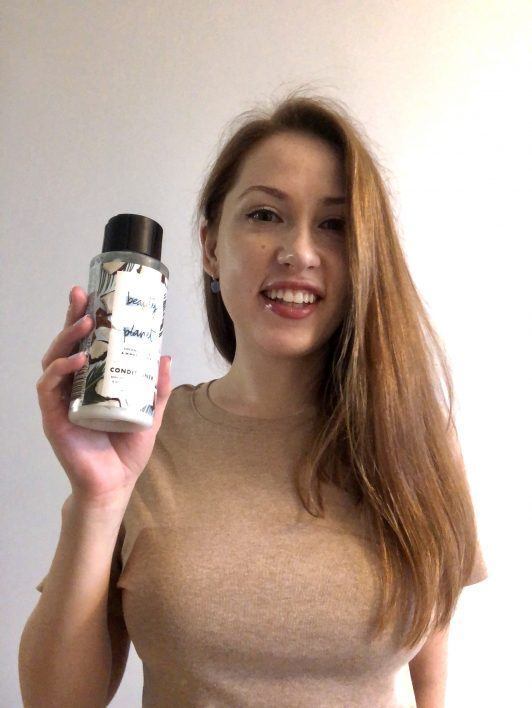mulher com cabelo ruivo longo segurando produto na mão