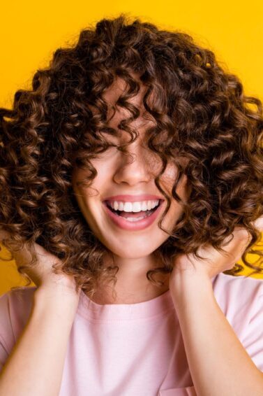 mulher sorrindo mexendo no cabelo