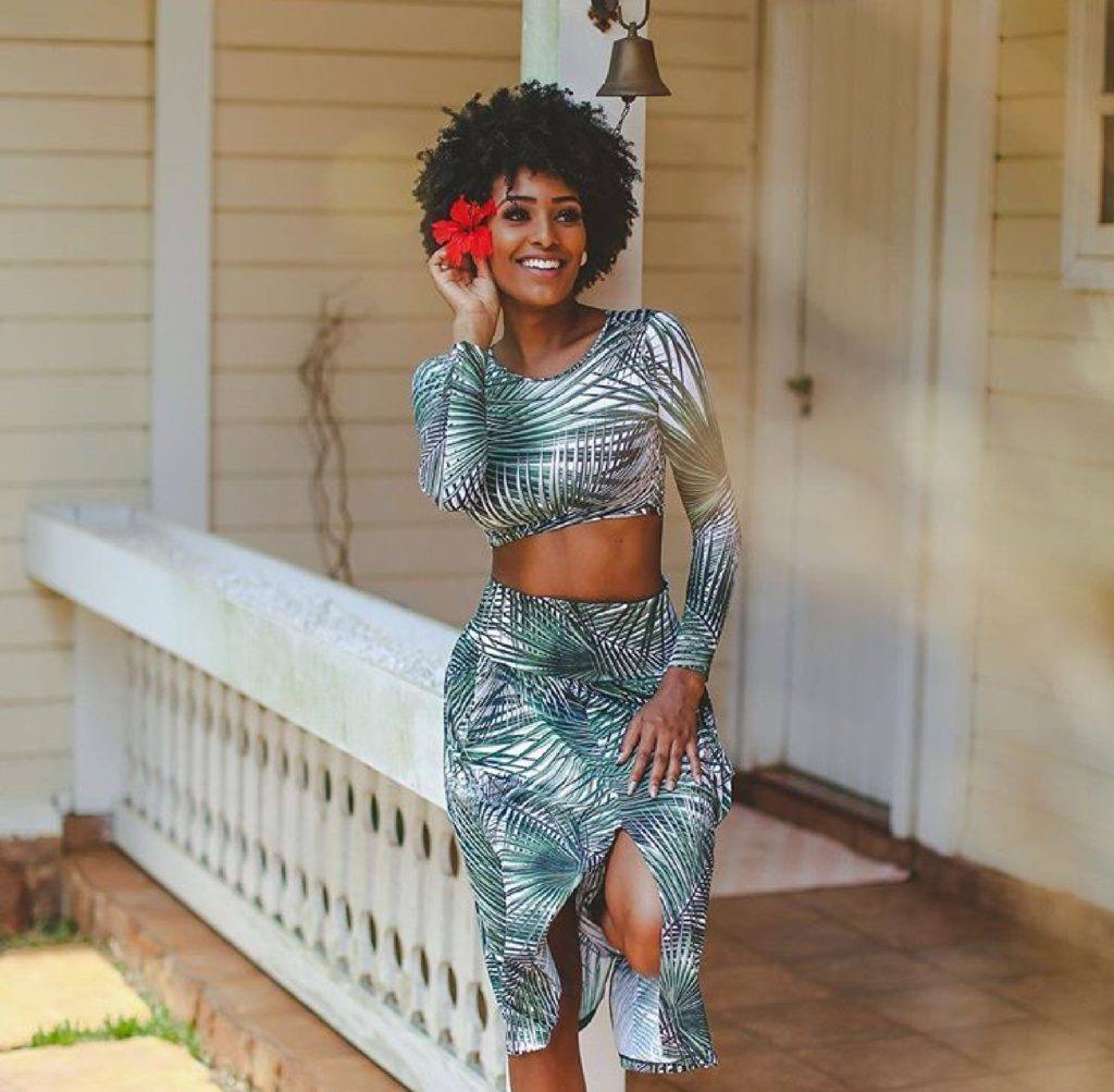 Mulher com cabelo curto crespo enfeitado com flor vermelha