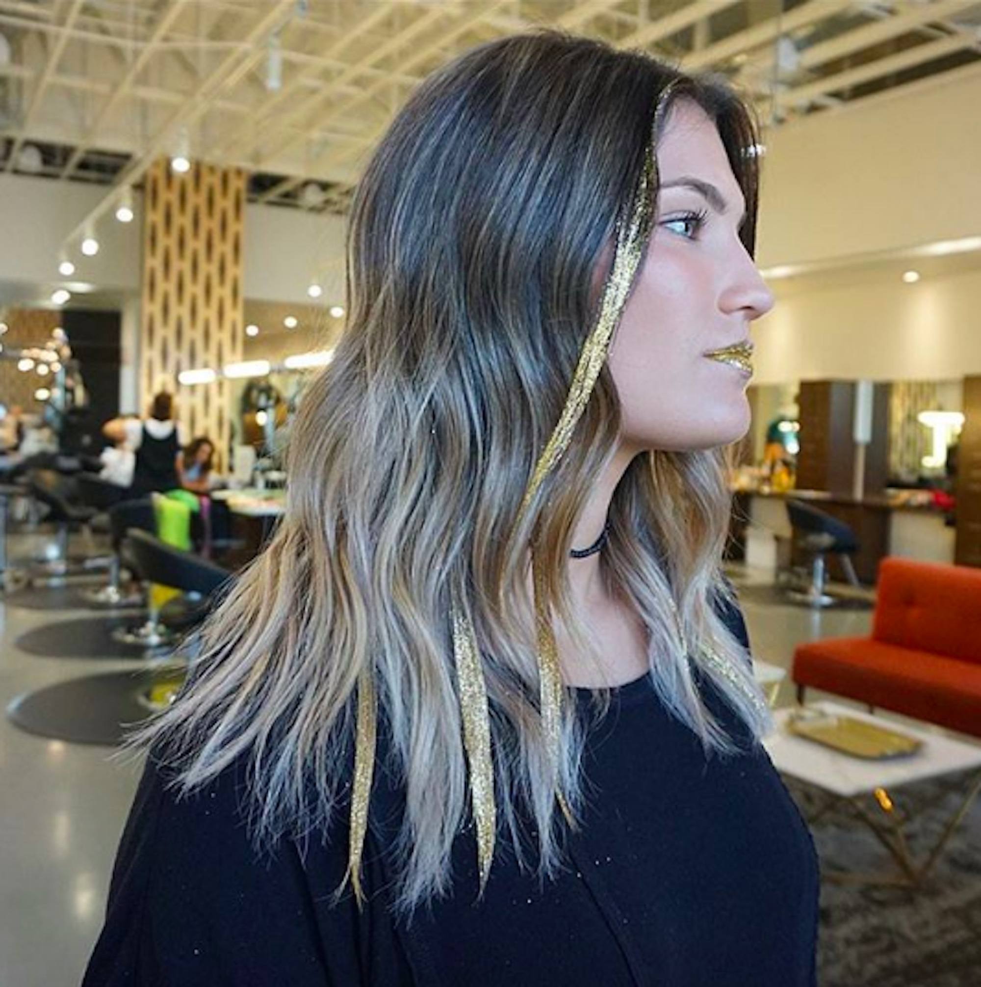 Mulher com cabelos loiros e mechas de glitter dourado