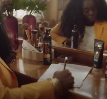 mulher escrevendo em papel com produtos tresemmé na mesa