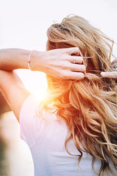 mulher de costas com cabelo longo ondulado loiro