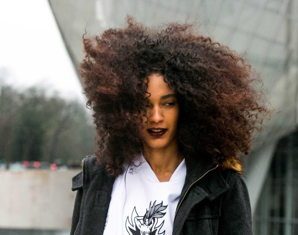 Mulher com cabelo afro poderoso mostra como proteger o cabelo do vento