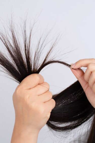 mulher segurando pontas do cabelo com pontas duplas