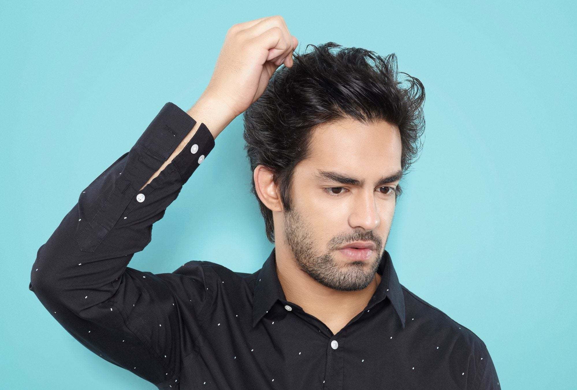 modelo masculino de cabelo liso arrepiado, com a mão na cabeça.