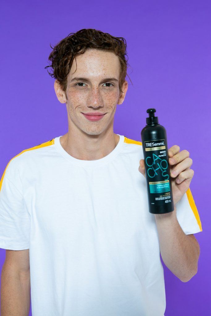 Homem ruivo de cabelo curto segurando produto