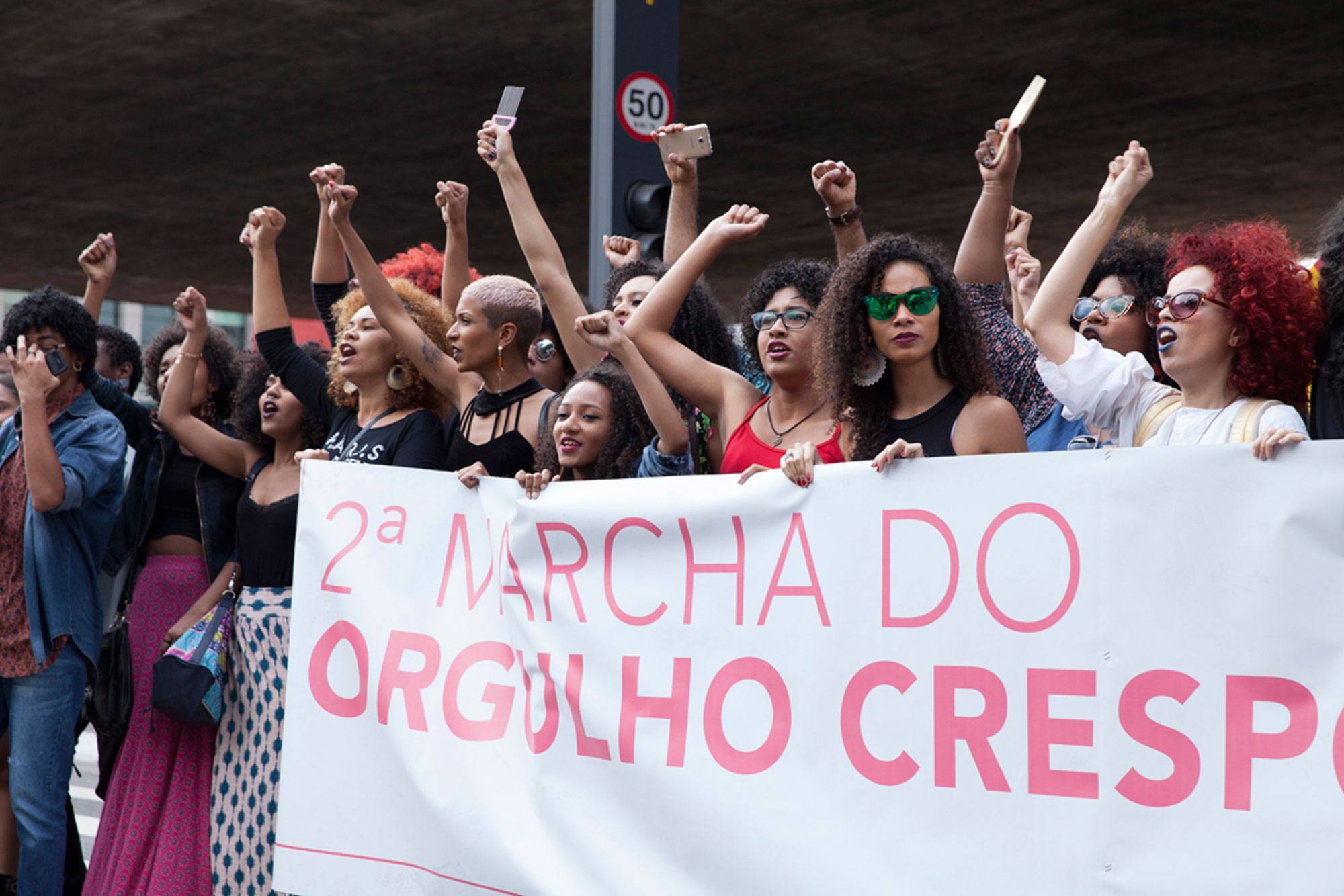 Mulheres e homens de cabelo crespo reunidos na marcha do orgulho crespo