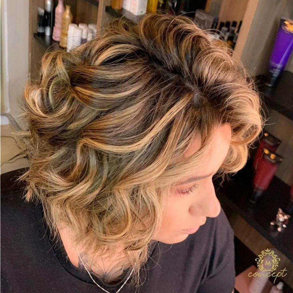 mulher com cabelo curto ondulado na cor morena iluminada mel