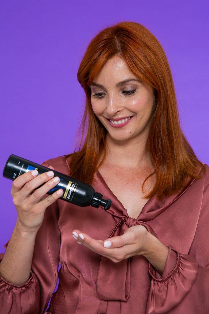 Modelo aplicando produto no cabelo