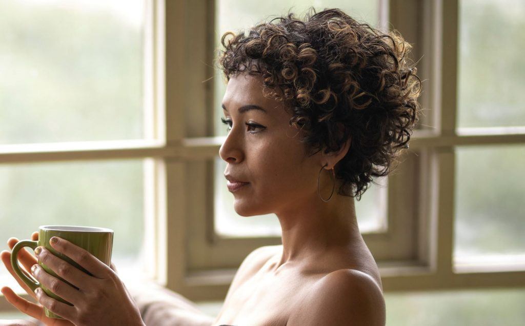Mulher é vista de perfil, dentro da banheira, com uma caneca na mão