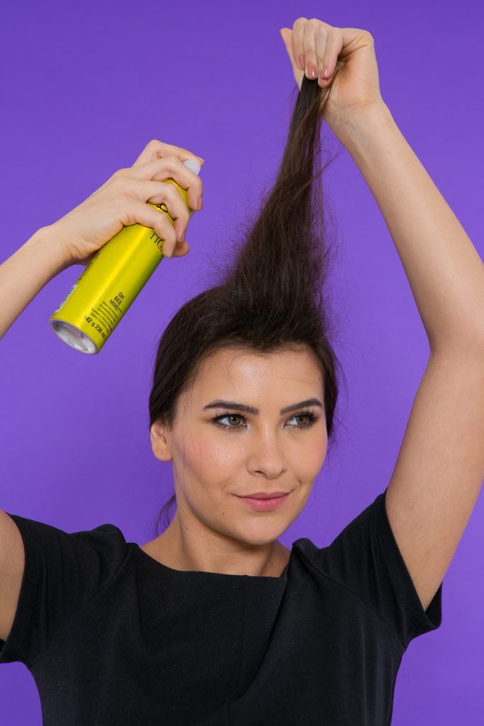 Modelo aplica shampoo seco para fazer trança com topete