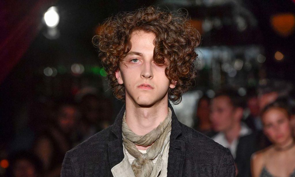Homem de cabelo cacheado assimétrico usa casaco preto