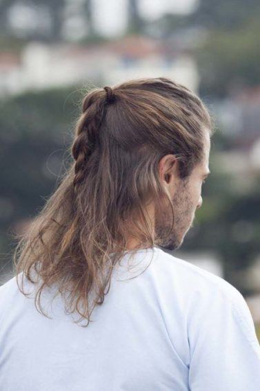 Homem loiro usa emia trança no cabelo loiro médio e blusa branca
