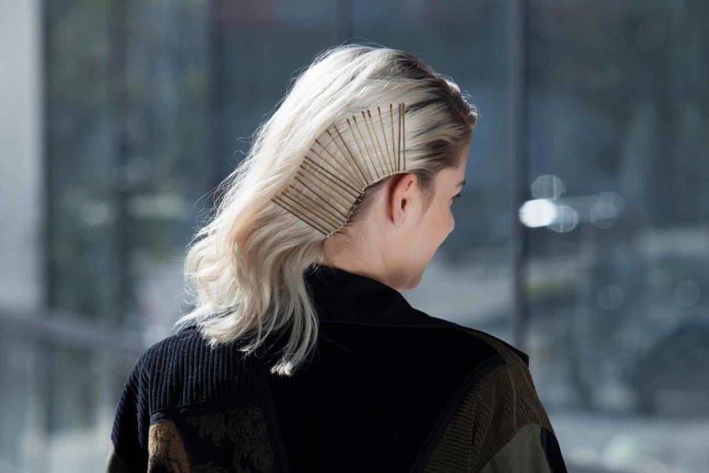 Mulher loira mostra como usar o grampo, com vários acessórios no cabelo