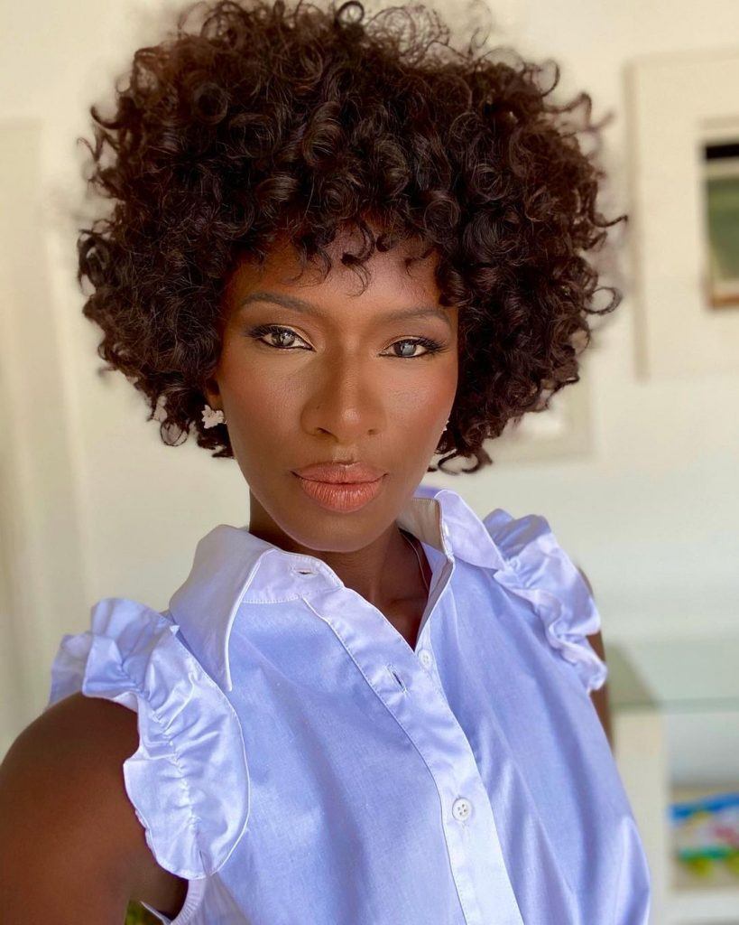 mulher com corte curto em camadas e cabelo cacheado castanho