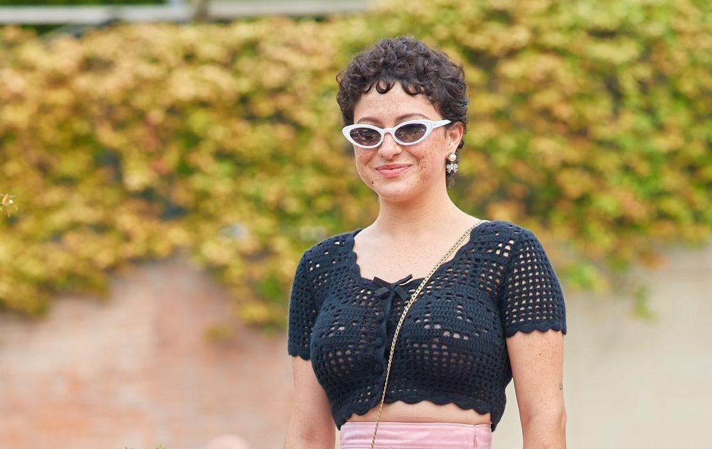 A atriz Alia Shawkat usa cabelos cacheados curtinhos e óculos de sol