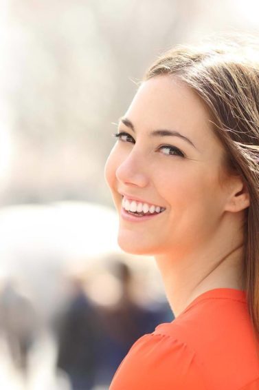 mulher sorrindo com cabelos castanho liso: suor danifica o cabelo
