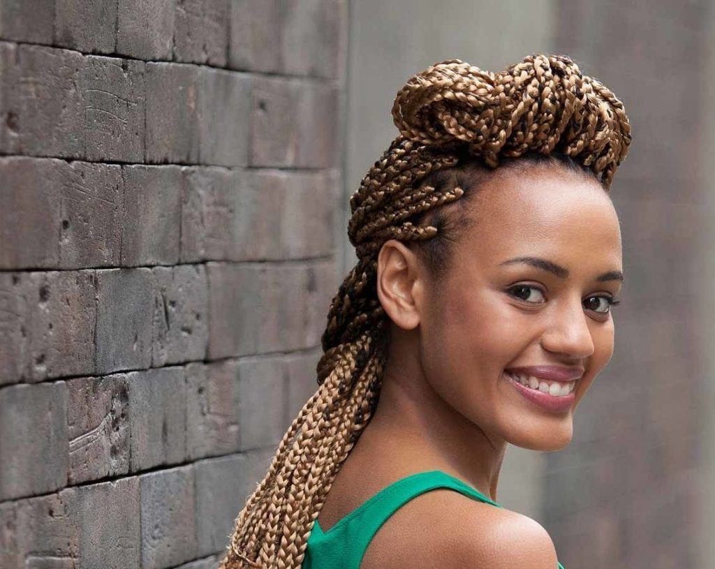 Mulher com cabelo longo e trancinhas loiras por todo o comprimento, com topete no topo da cabeça
