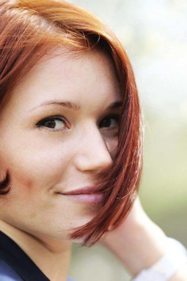 Modelo com cabelo ruivo e corte chanel assimétrico.