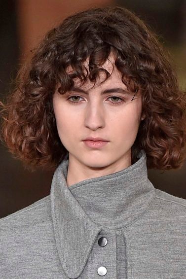 Modelo com corte médio cacheado com franja